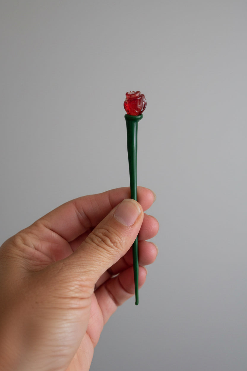 Hand holding a green and red object against a plain background