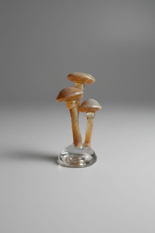 Decorative mushroom sculpture on a glass base with flowers and grass in the background